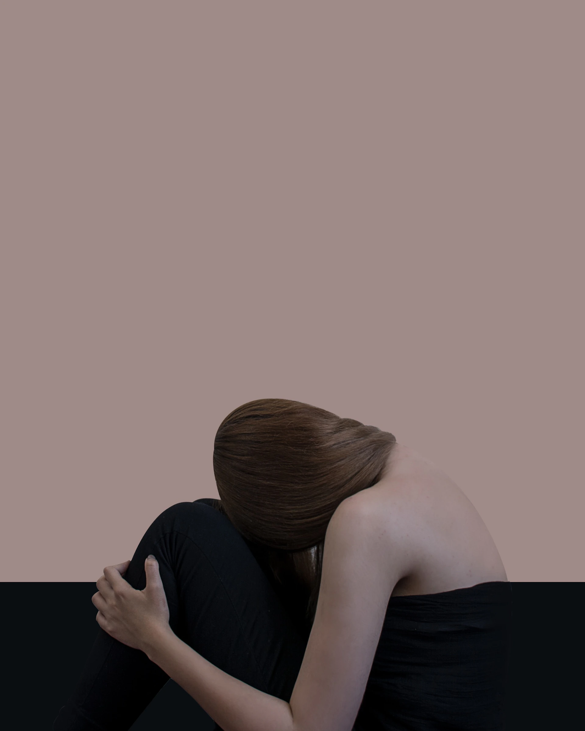 woman with blond hair lying her head on her knee on a black sofa