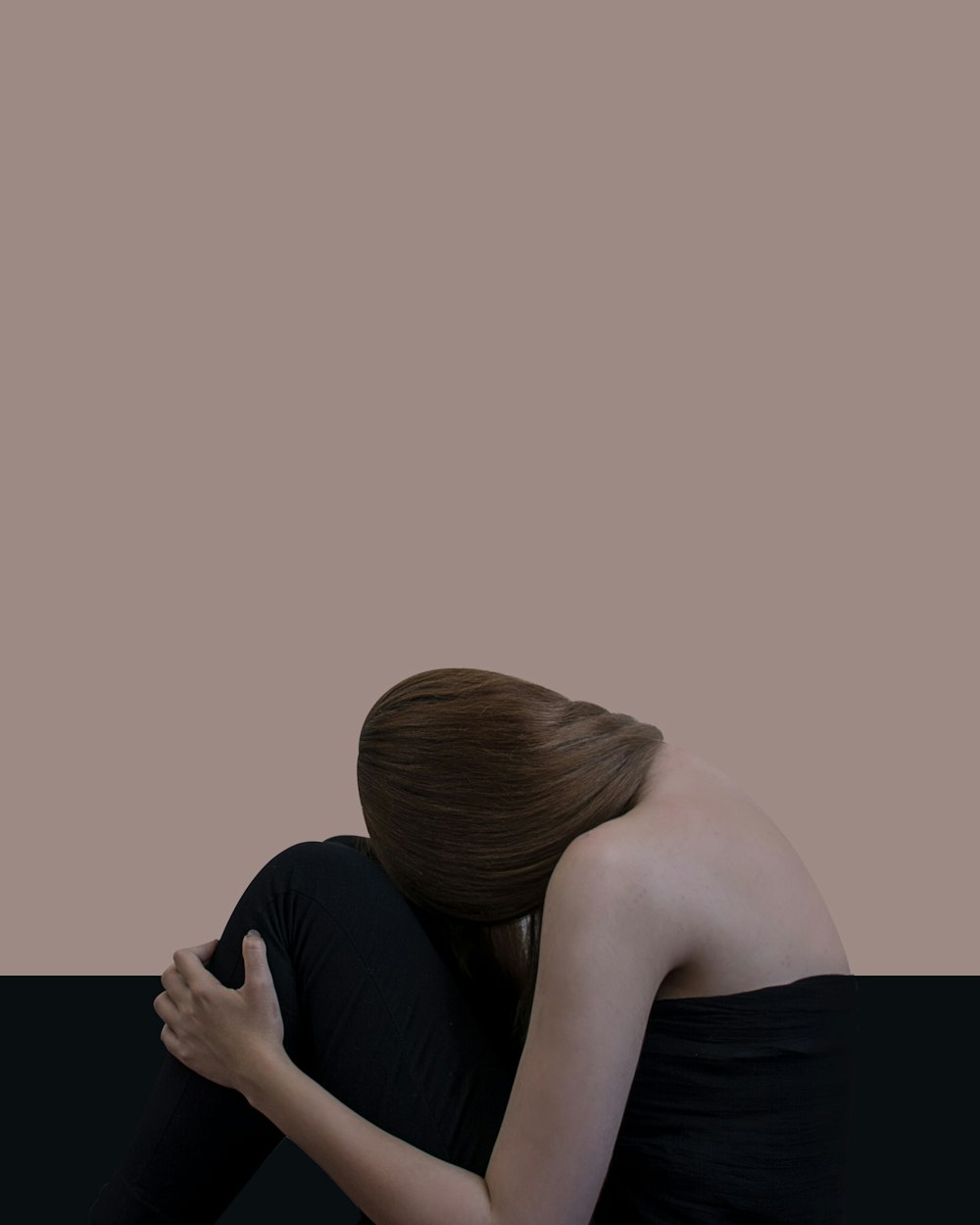 mujer de pelo rubio acostada con la cabeza sobre la rodilla en un sofá negro