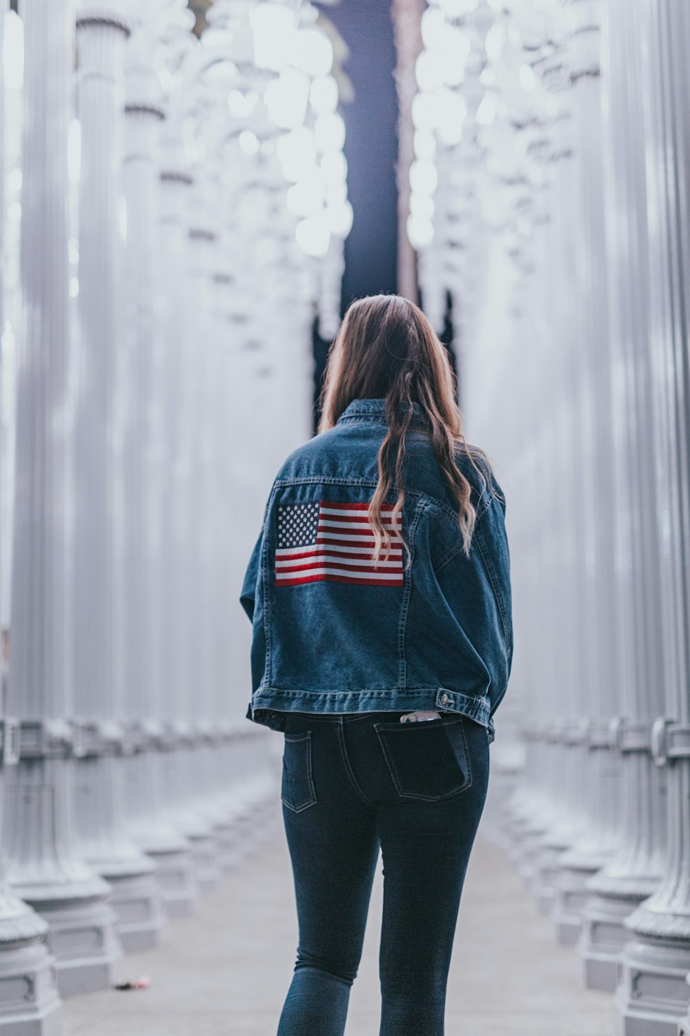 woman in blue denim jacket standing near pedestals