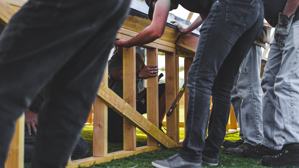 group of people repairing brown wooden fence during daytime