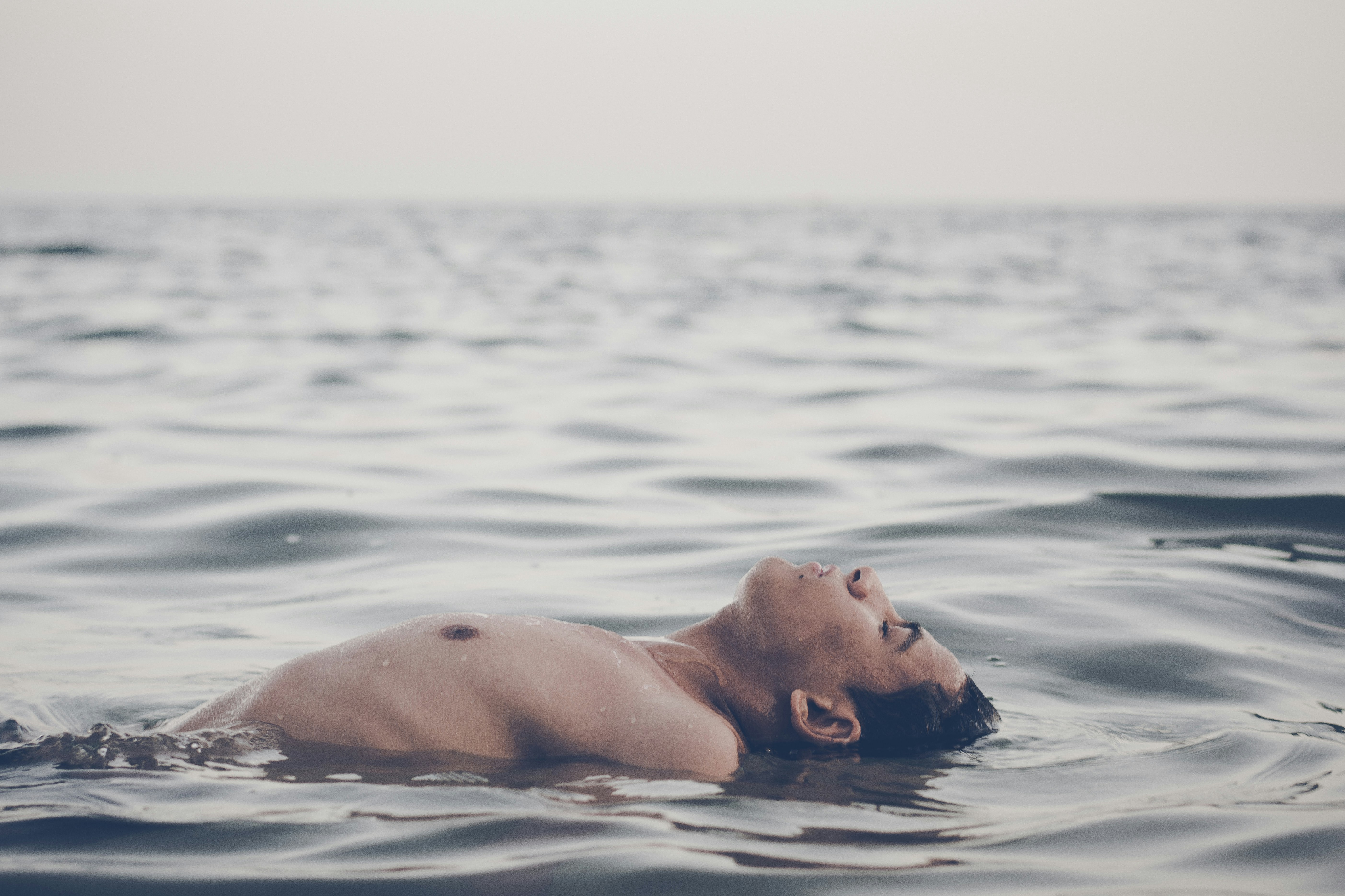 Man Floating On Water During Day Photo Free Grey Image On Unsplash