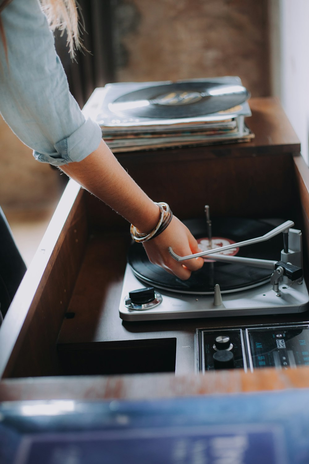 Persona sosteniendo un tocadiscos de vinilo gris y negro