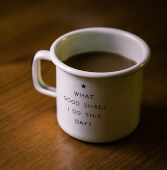 white and black ceramic cup filled with brown liquid on brown wooden sufface