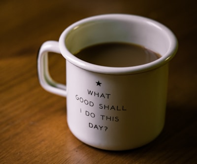 white and black ceramic cup filled with brown liquid on brown wooden sufface