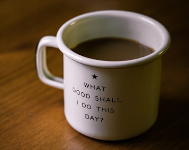 white and black ceramic cup filled with brown liquid on brown wooden sufface