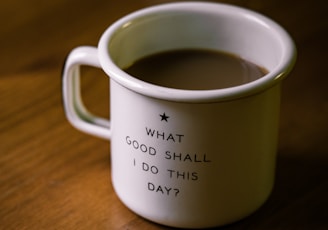 white and black ceramic cup filled with brown liquid on brown wooden sufface