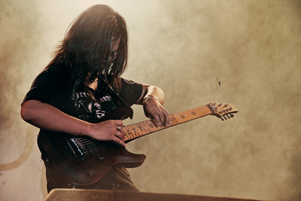 person holding black electric guitar