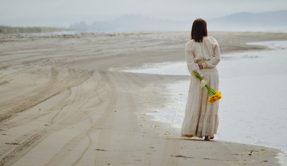 바닷가 근처에 서서 노란 꽃잎을 들고 있는 여자