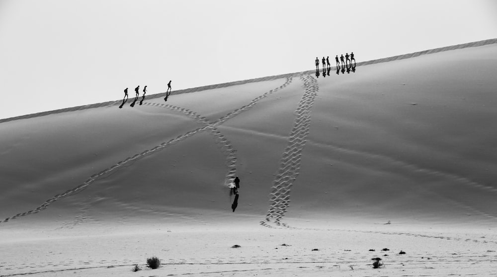 foto em tons de cinza de pessoas caminhando no deserto