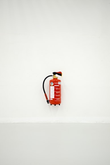 Image Alt Text: A red fire extinguisher mounted on an empty white wall