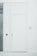 A minimalist white door is set within a white wall. The door has two metallic doorknobs, one above the other, and there is a small black square panel to the side of the door. Adjacent to the door, a frosted glass panel is visible. The design is clean and modern, with a monochromatic color scheme.