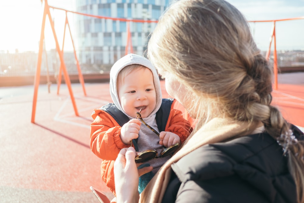 woman holding toddler on carrier