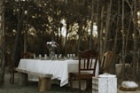 Outdoor dining setup with guests enjoying a barbecue feast surrounded by lush forest.