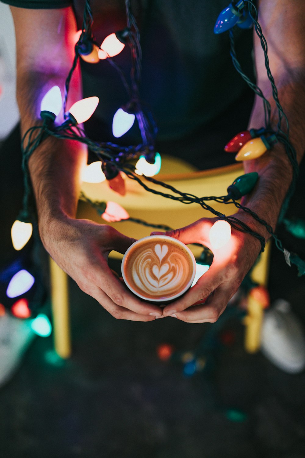 person holding mug with liquor and string light