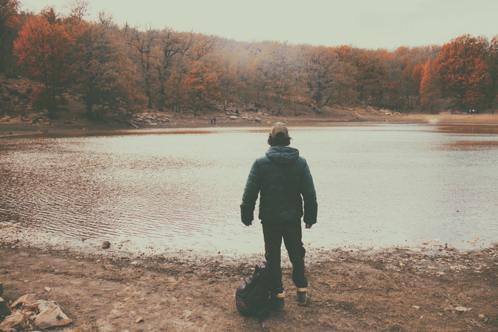 man wearing black jacket standing near river during daytime