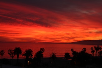 A breathtaking sunset over a luxury oceanfront estate in Hawaii with palm trees swaying gently.