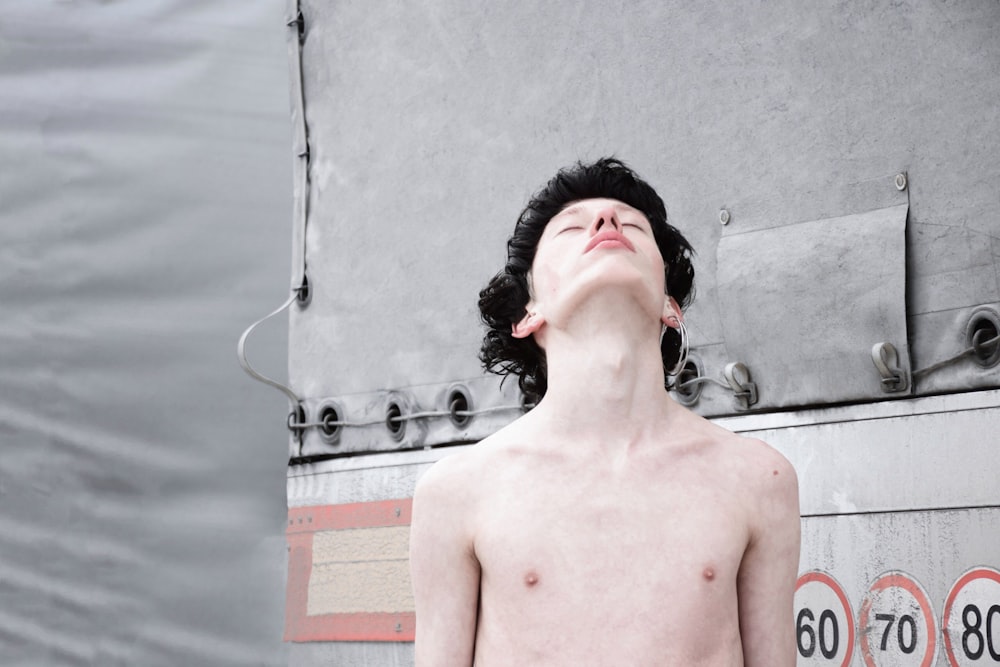 topless man standing near signage while closing his eyes