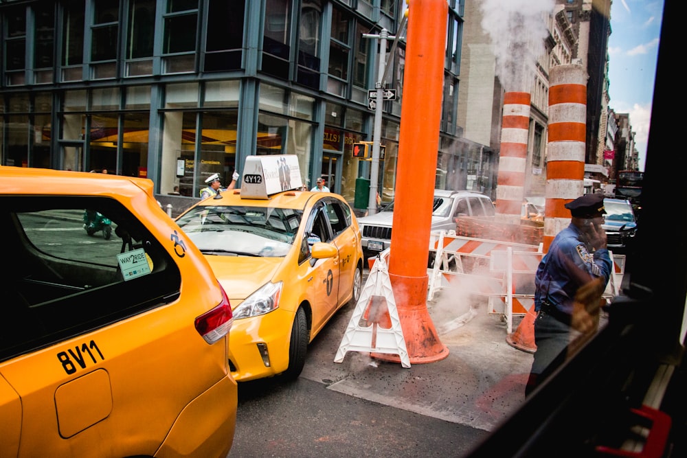 a yellow taxi cab parked next to a traffic cone