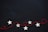 Five white star-shaped ornaments are placed against a dark background. A red string is weaved through the stars, forming loops and curves.