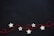 Five white star-shaped ornaments are placed against a dark background. A red string is weaved through the stars, forming loops and curves.