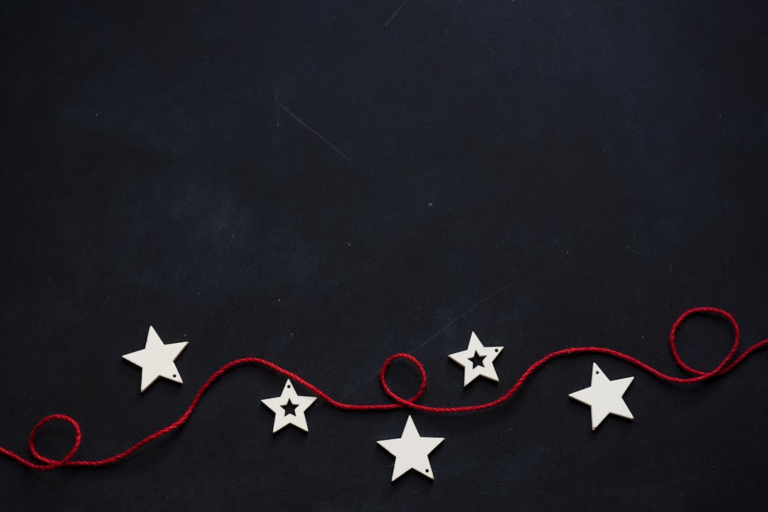 white stars cutout on black surface with red string,