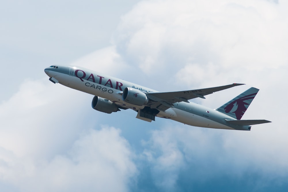 gray and white Qatar Cargo plane on mid sky taken under white cloudy sky taken at daytime