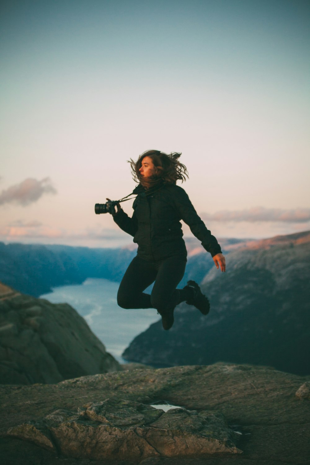 카메라를 들고 점프하는 여자의 선택적 초점 사진