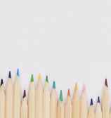 colored pencil lined up on top of white surface