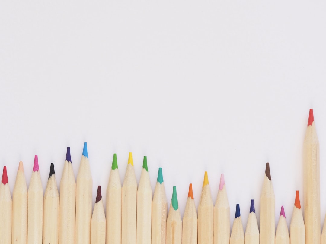 colored pencil lined up on top of white surface,