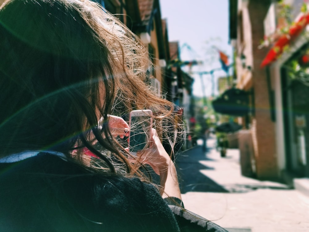 woman in black top holding white smartphone