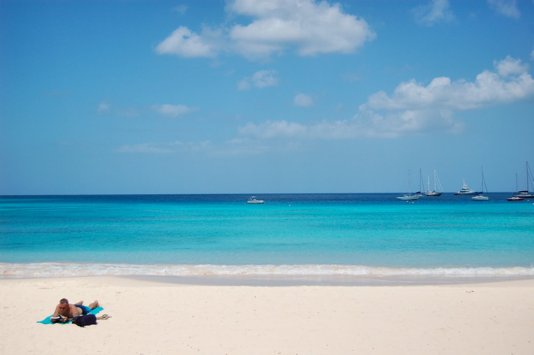 man laying on beach in distant of boats