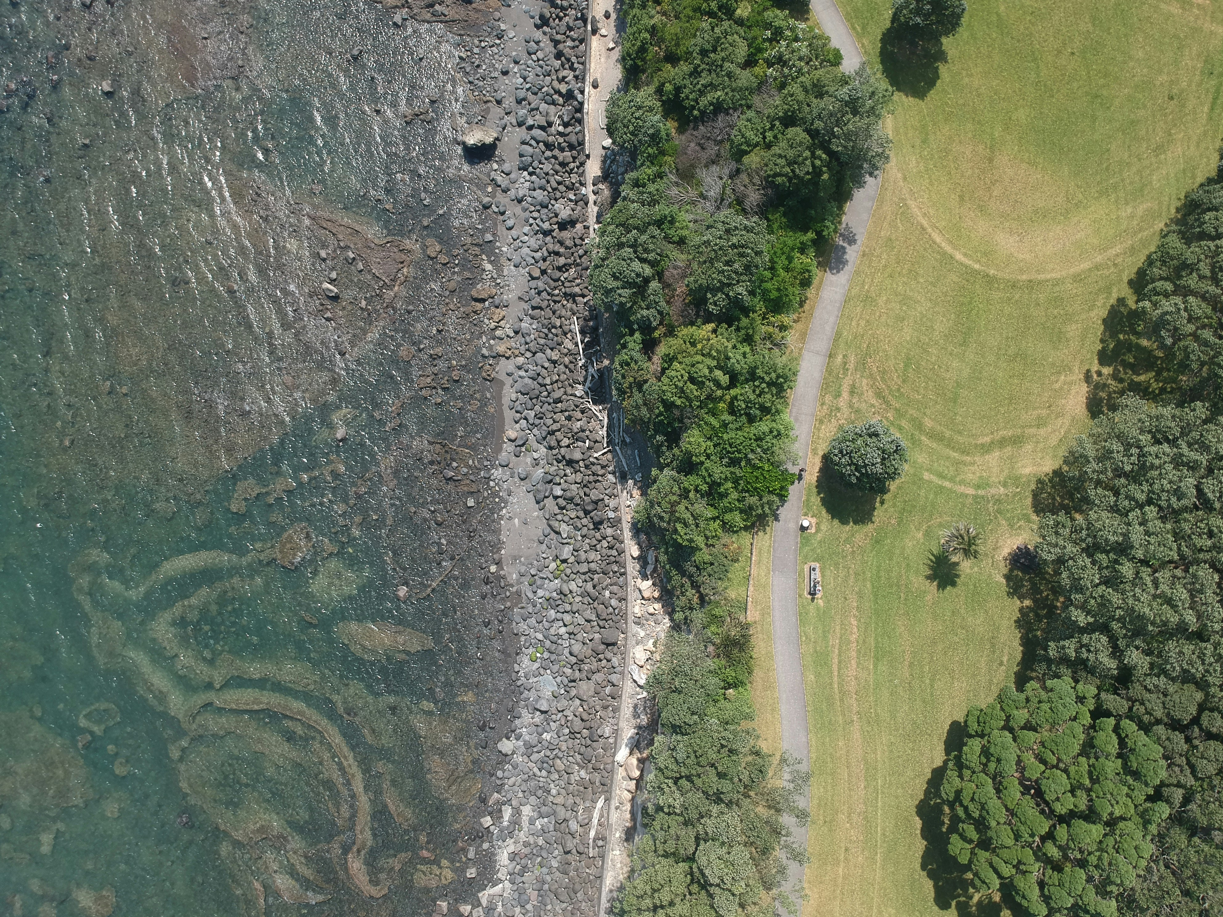 An aerial shot of a picturesque coastline where the turquoise water meets colorful cliffs. A hidden gem for travelers.