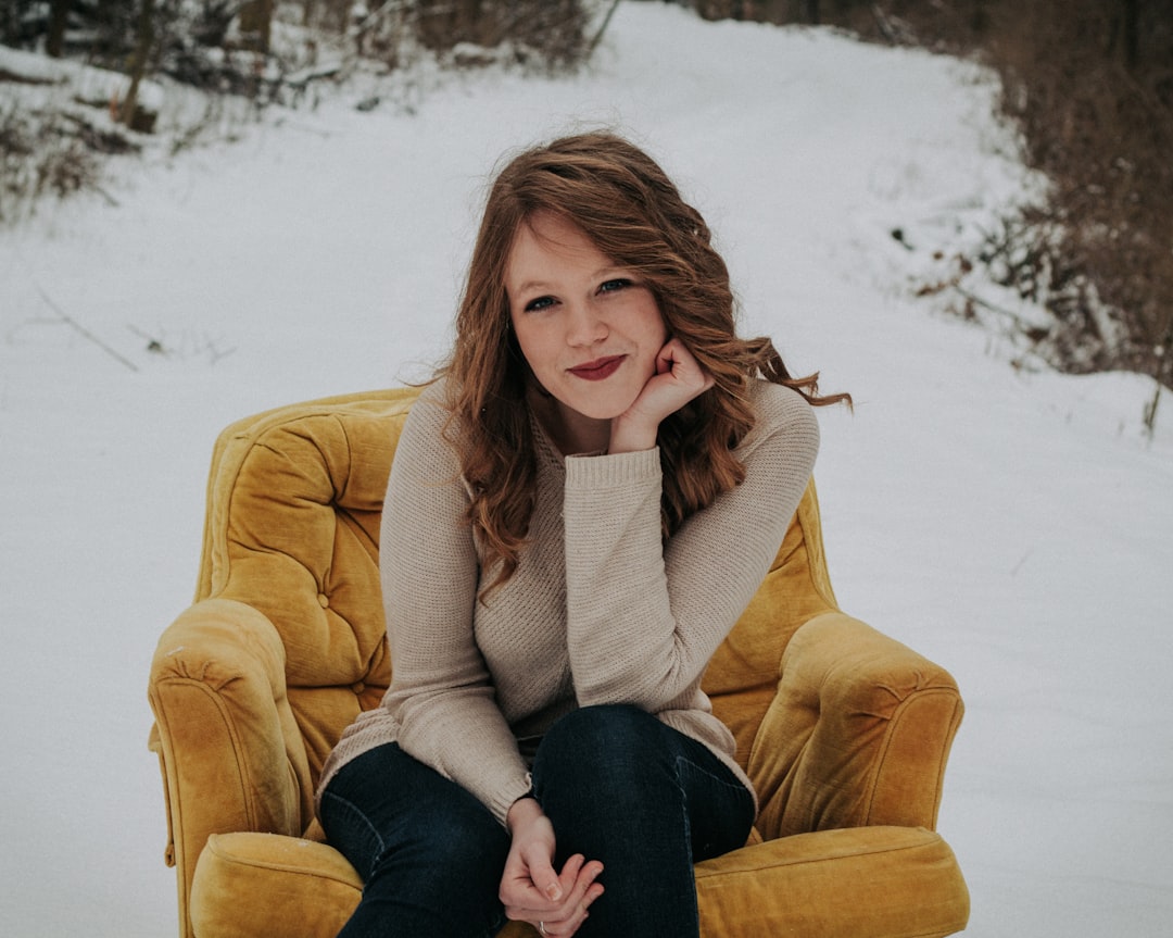 woman sitting on sofa chair surrounded with snow and trees