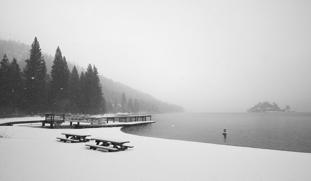 snow-covered picnic bench near body of water