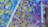 A vibrant mosaic artwork composed of multiple small, colorful tiles arranged in a dynamic, abstract pattern. The tiles vary in color and size, creating an intricate and lively visual effect.