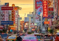 vehicles on street between buildings with Kanji script signage during golden hour