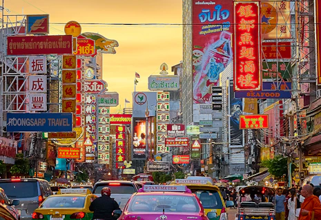 vehicles on street between buildings with Kanji script signage during golden hour
