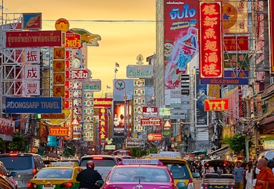 vehicles on street between buildings with Kanji script signage during golden hour