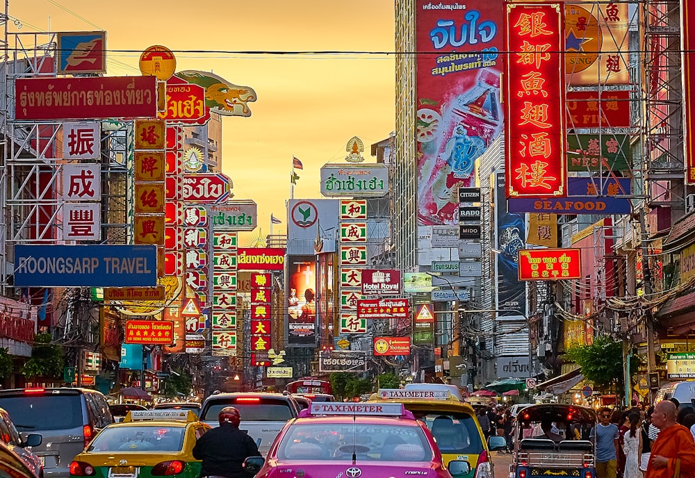 vehicles on street between buildings with Kanji script signage during golden hour