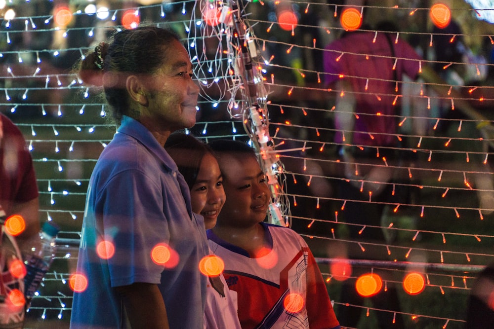 woman with girl and boy standing tunnel of string lights