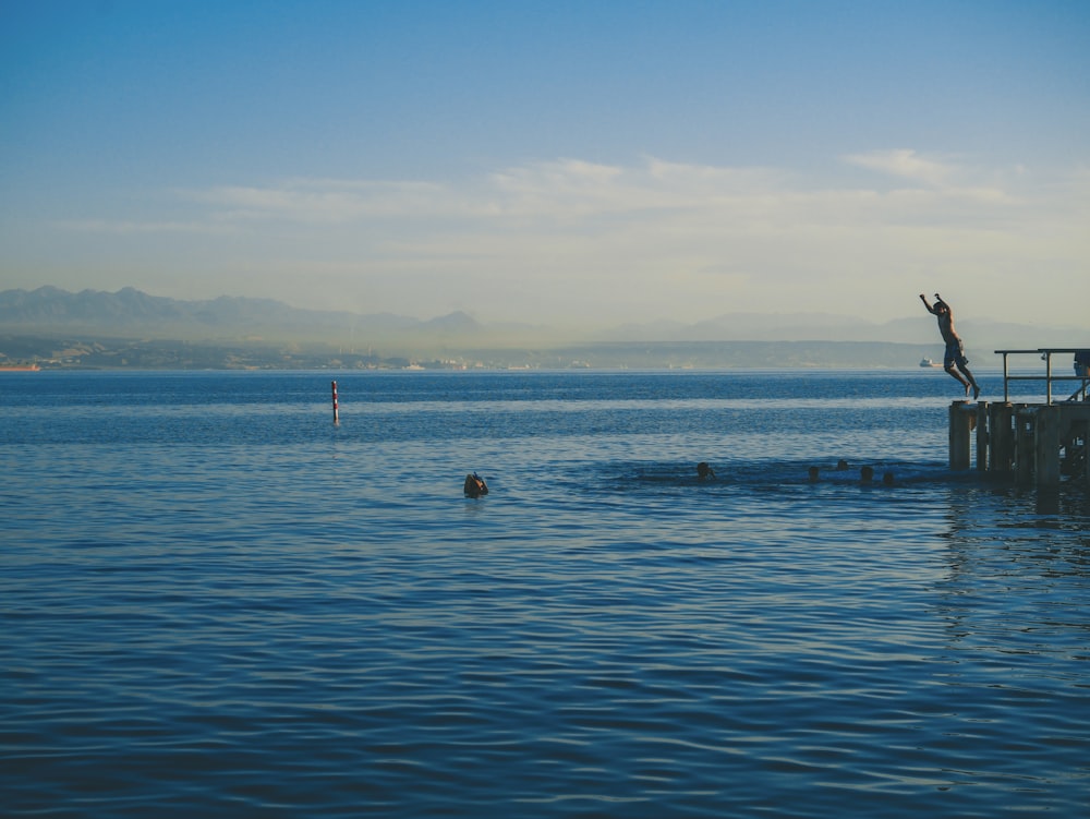 man about to jump on ocean at daytime