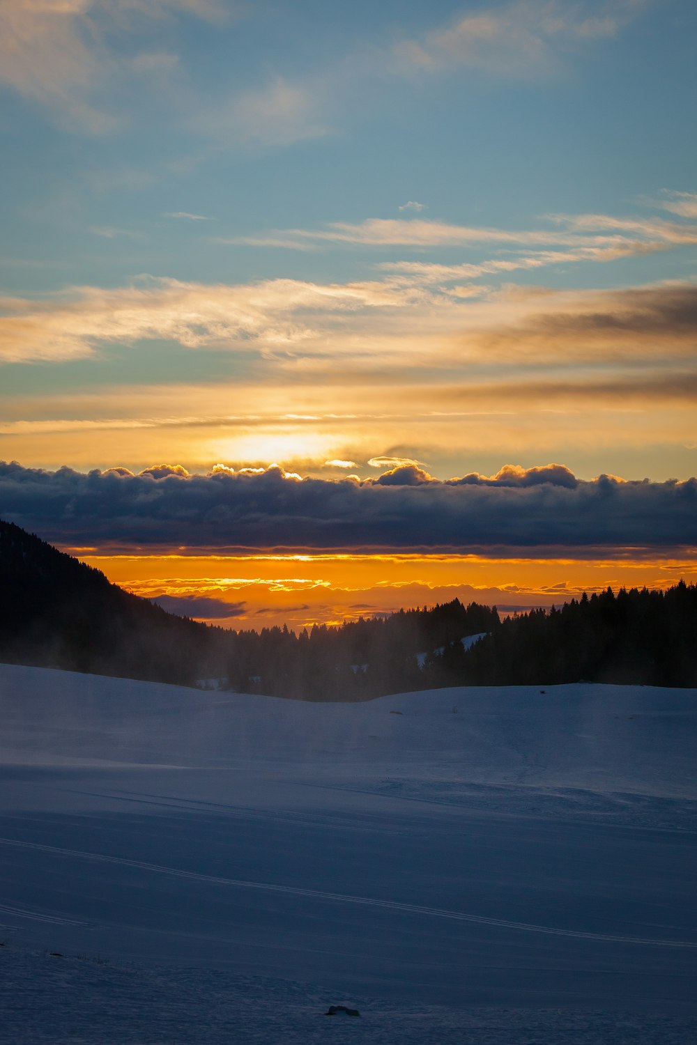 snow covered ground under sunset sky