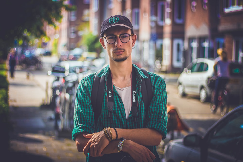 man in green shirt wearing black Canon DSLR camera in tilt shift photography