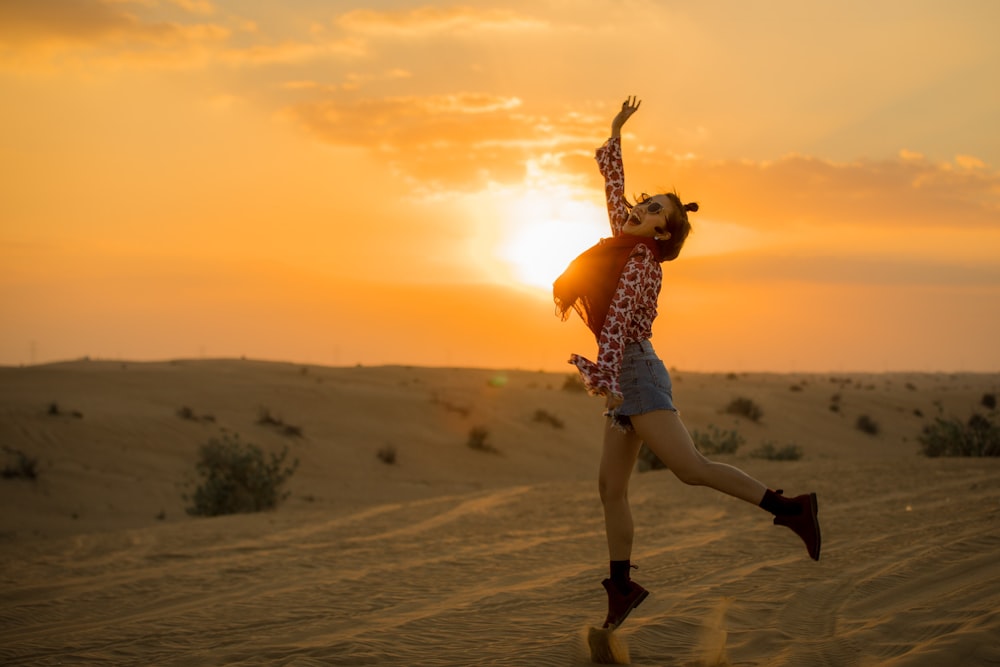 femme sautant sur le désert pendant l’heure dorée