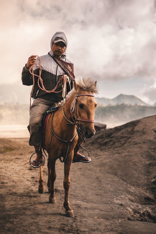 man riding horse under cloudy skies in Mount Bromo Indonesia