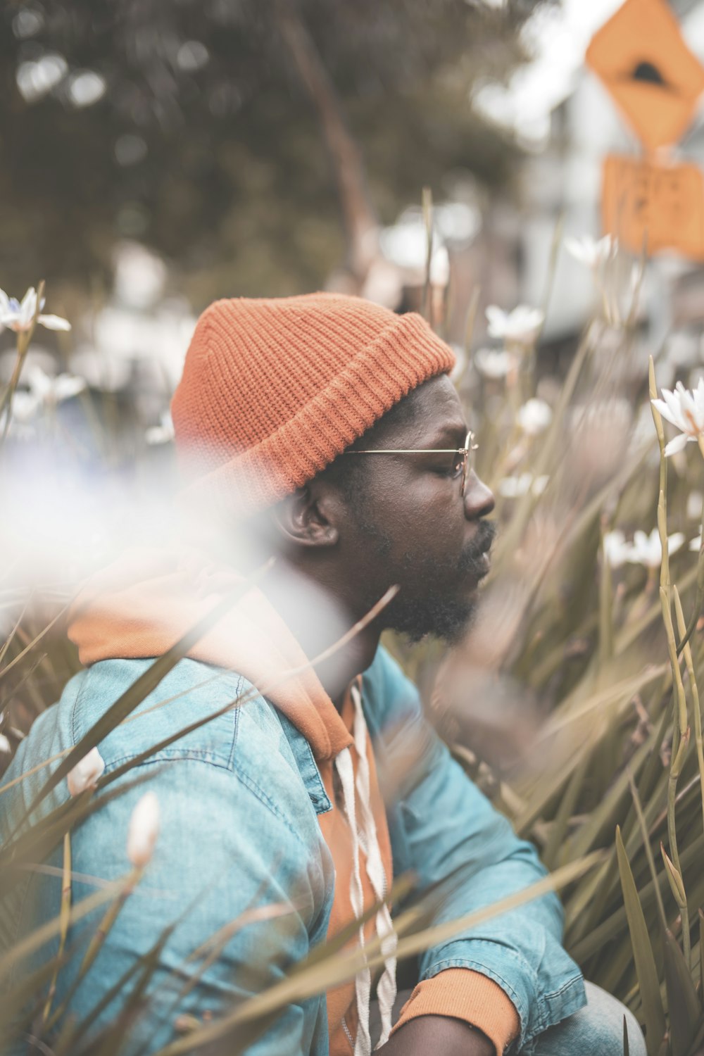 Fotografía de enfoque selectivo de hombre con gorro de punto naranja junto a hierbas marrones