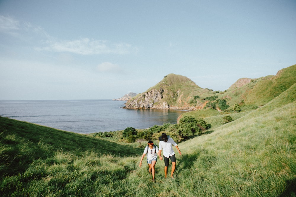 photo de paysage de couple marchant sur l’herbe verte