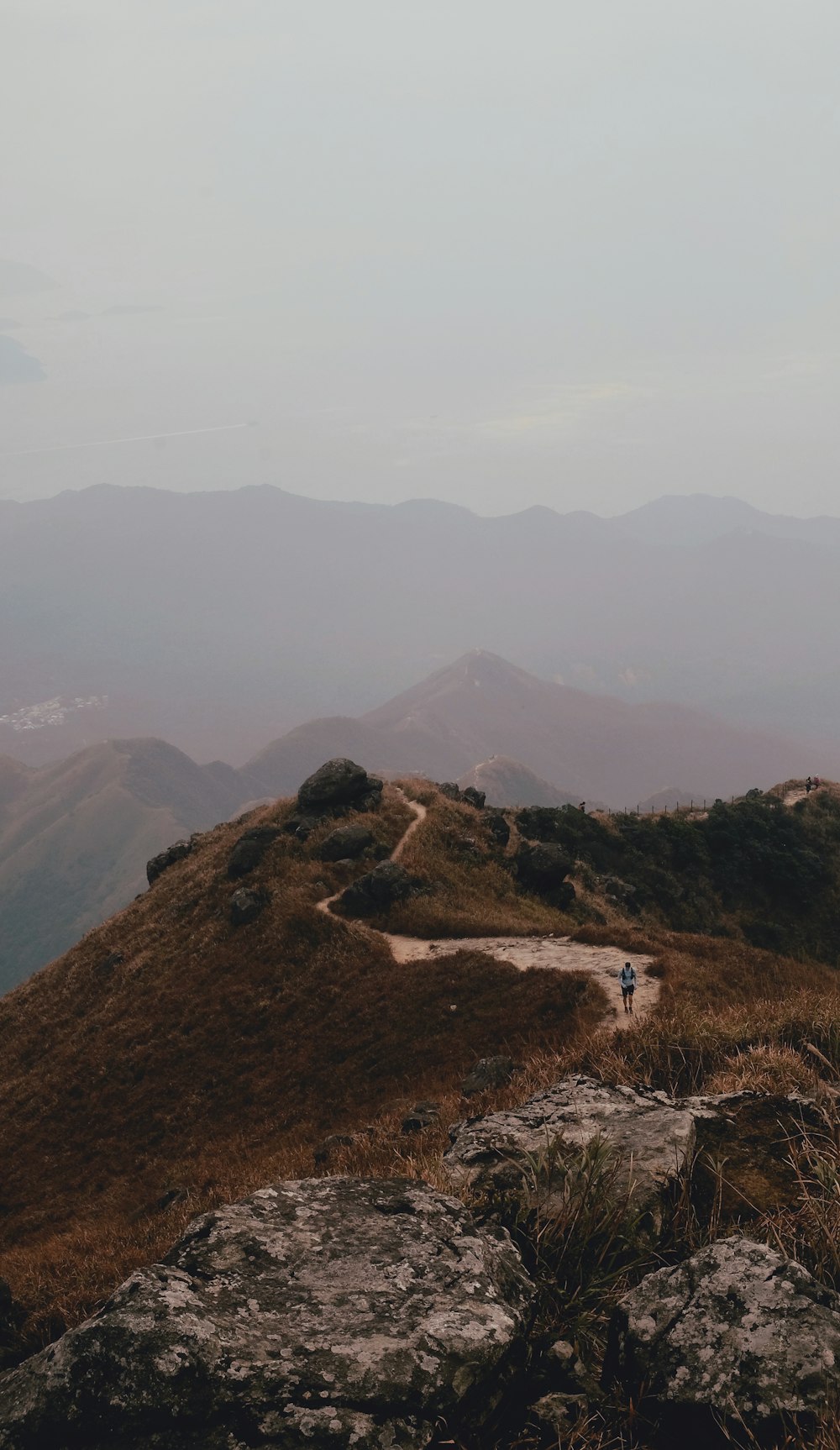 man waking across winding road near mountain ranges