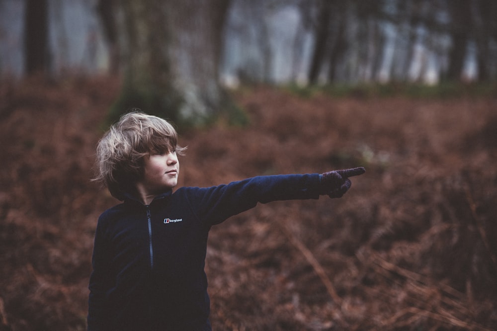 boy standing pointing finger on right