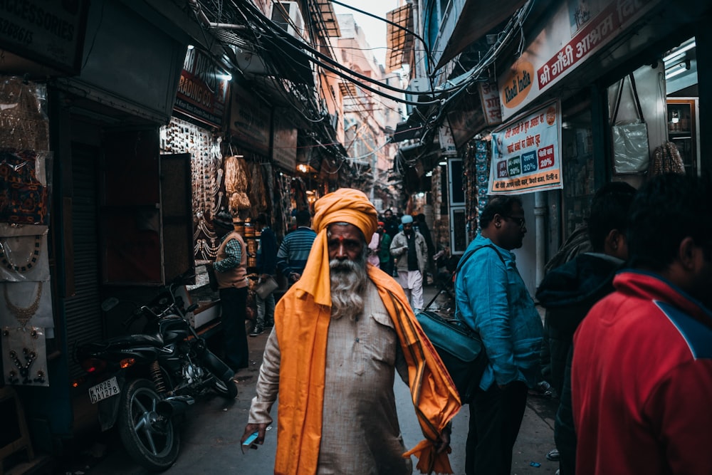 man in orange turban standing in middle of road